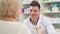 Cheerful pharmacist selling medication to senior customer