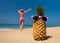 Cheerful pineapple glasses and a woman in a bikini sunbathing on the beach on sea backgrounde beach on sea background.