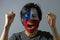 Cheerful portrait of a man with the flag of the Chile painted on his face on grey background.