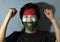 Cheerful portrait of a man with the flag of Tajikistan painted on his face on grey background. The concept of sport.