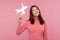 Cheerful positive brunette woman holding in hand paper plane looking with toothy smile, air hostess preparing for flight