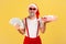 Cheerful positive elderly man in sunglasses and santa claus hat holding fan of dollars and gift box smiling at camera, preparing