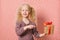 cheerful preschooler girl with a gift on a red striped background, a gift with a red ribbon