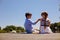 Cheerful preteen boy feeding his sister on pier