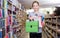 Cheerful preteen girl student holding stack of school stationery in shop