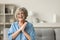 Cheerful pretty older woman in elegant glasses sitting on couch