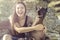 Cheerful pretty young girl sitting and hugging her dog xoloitzcuintli on the stoun beach at sunset