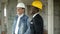 Cheerful professional construction manager and afro businessman talking and smiling at construction site