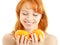 Cheerful redhead holding two oranges over white