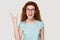 Cheerful redhead millennial woman showing rock and roll hand gesture