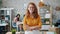 Cheerful redhead woman in glasses standing in office with arms crossed smiling