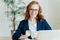 Cheerful redhead woman prepares application letter, sits in front of opened laptop computer, browses internet and seeks for job