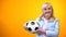 Cheerful retiree woman holding football ball, sports betting, positive attitude