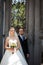 Cheerful, romantic couple of newlyweds posing near old gate