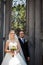 Cheerful, romantic couple of newlyweds posing near old gate