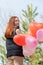 cheerful romantic woman walking outdoors with balloons