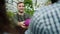 Cheerful salesman giving organic food to customer in greenhouse market