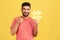 Cheerful satisfied man with beard in striped t-shirt showing thumbs up like gesture holding yellow hashtag sign, satisfied with