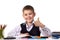 Cheerful satisfied pupil sitting at the desk with thumb up surrounded with stationery