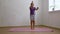 Cheerful school age girl in sportswear jump in place waving arms on gymnastic mat in empty room, free copy space. Home