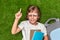 Cheerful schoolboy having idea on lawn