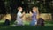 Cheerful schoolboy and schoolgirl playing clapping game sitting in park after teaching on school break