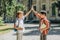 Cheerful schoolboys giving high five while standing in schoolyard