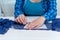 A cheerful seamstress in a blue checked shirt is working in her workshop. close-up, on a table next to a sewing machine