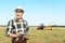 cheerful self-employed farmer in straw hat using digital tablet in field.
