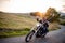 Cheerful senior couple travellers with motorbike in countryside.