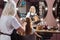 Cheerful senior hairdresser brushing girls hair