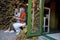 Cheerful senior ladies friends with cups of drinks sit on bench in cafe yard