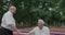 Cheerful senior man coming to his friend in a park, rejoicing and shaking hands