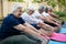 Cheerful senior woman with friends doing stretching exercise