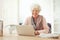 Cheerful Senior Woman at Home with Laptop