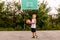 A cheerful seven-year-old boy in basketball uniform plays with a ball on an open basketball court in the summer