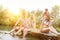 Cheerful shirtless man spraying water with squirt gun on friends sitting at pier over lake