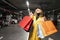 Cheerful shopper woman with purchases walking on the parking lot of shopping center