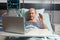 Cheerful sick senior man waving at camera during video conference