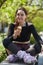 Cheerful skate female eating an ice cream on a bench in a green park. Happy young adult roller blader person wearing modern inline