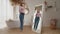 Cheerful slim adult woman in loose jeans checking in mirror her weight loss success at home