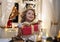 Cheerful small girl sitting indoors at Christmas, holding present.