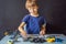 Cheerful smart schoolboy sitting at the table and constructing a robotic device at home