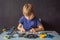 Cheerful smart schoolboy sitting at the table and constructing a robotic device at home