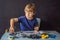 Cheerful smart schoolboy sitting at the table and constructing a robotic device at home