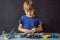 Cheerful smart schoolboy sitting at the table and constructing a robotic device at home