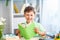 Cheerful smiling boy of 7 years old, Caucasian, reading a book at the table