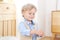 A cheerful and smiling boy holds a figure in his hands. Child in kindergarten. Portrait of fashionable male child. Smiling boy pos