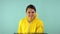 Cheerful and smiling cleaning lady in a yellow suit on a blue background. The concept of professional house cleaning. A