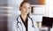 Cheerful smiling female doctor standing with arms crossed in clinic. Portrait of friendly physician woman. Medicine